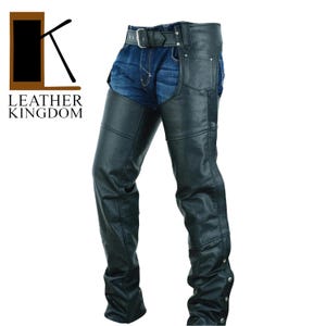 Könnte beinhalten: Schwarze Lederchaps mit Gürtel und silberner Schnalle. Die Chaps haben ein klassisches Design mit mehreren Paneelen und dekorativen Nähten. Am unteren Ende befinden sich silberne Druckknöpfe. Das Logo "LEATHER KINGDOM" ist links oben sichtbar.
