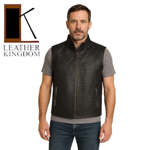 Op de afbeelding: Een zwart leren vest met een ritssluiting en een krokodil-geprägd patroon. Het vest heeft een opstaande kraag en twee zakken aan de voorkant.  LEATHER KINGDOM is onder de afbeelding gedrukt.