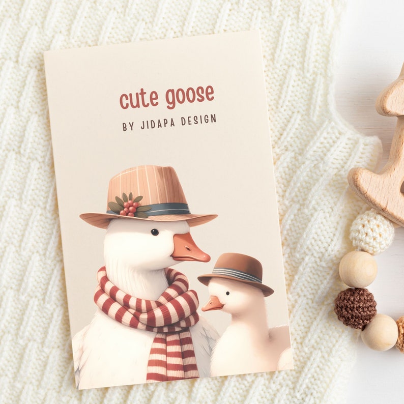 May include: A cute goose wearing a brown and white striped hat with a red berry accent and a red and white striped scarf. The goose is standing next to a smaller goose wearing a brown hat with a white stripe. The text "cute goose by JIDAPA DESIGN" is printed on the card.