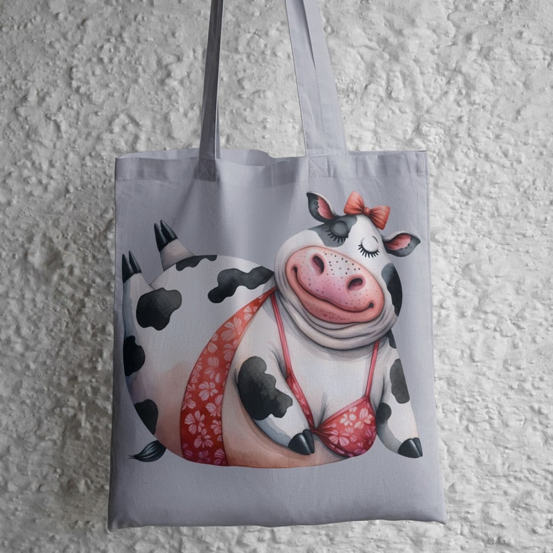 May include: A gray tote bag with a cartoon illustration of a black and white cow wearing a pink bikini. The cow is smiling and has its eyes closed.