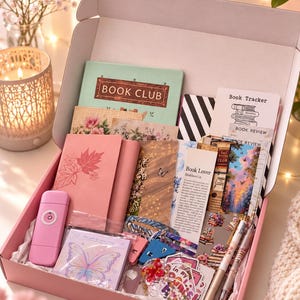 Peut inclure: Une boîte cadeau rose remplie d'articles de papeterie comprenant un carnet vert menthe étiqueté BOOK CLUB, un journal rose gaufré de feuilles, une lampe portable rose, un bloc-notes papillon, des suivis de lecture, des marque-pages et des autocollants.