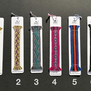 May include: Six hand-woven bookmarks with various geometric patterns and colors, including yellow, purple, teal, pink, blue, and green. Each bookmark is attached to a white card with the text "MC Crafts Handmade" and the words "Hand Woven Bookmark".