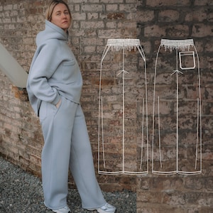May include: A light blue hooded sweatshirt and matching sweatpants. The sweatpants have a drawstring waistband and a pocket on the right leg. The outfit is shown on a person standing in front of a brick wall.