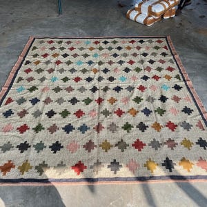 May include: A beige area rug with a geometric pattern of colourful diamonds. The rug has a dark brown border.
