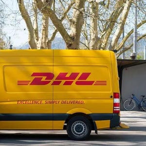 May include: A yellow DHL delivery van with the DHL logo in red. The van has the text "EXCELLENCE. SIMPLY DELIVERED." on the side. A person in a red and yellow vest stands near the van. A bicycle is parked nearby.