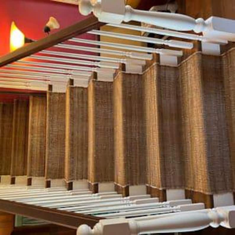 Op de afbeelding: Natuurlijke vezel traptreden in een lichtbruine kleur. De treden zijn geweven en hebben een subtiele textuur. De treden zijn ge&iuml;nstalleerd op een houten trap met wit geschilderde leuningen.