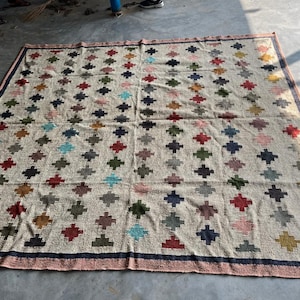 May include: A large, rectangular rug with a cream-coloured background and a geometric pattern of colourful diamonds. The diamonds are arranged in a grid pattern and are made of different colours, including red, blue, green, and yellow.