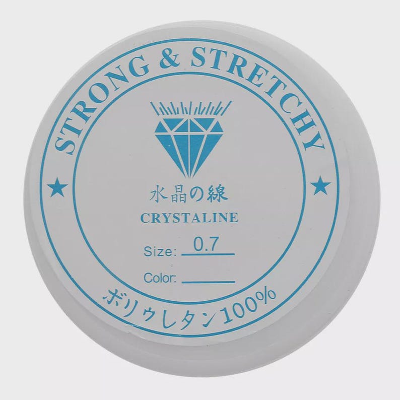 May include: A white spool of strong and stretchy crystalline thread. The label features blue text and a diamond graphic. Text includes "STRONG & STRETCHY", "水晶の線", "CRYSTALINE", "Size: 0.7", and "ボリウレタン100%"