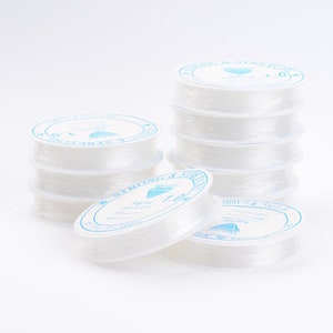 May include: A stack of clear elastic string spools with blue and white labels that say "Strong & Stretchy" and "1.0mm".