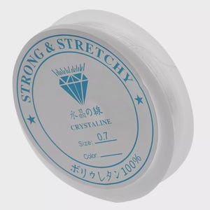 May include: A spool of clear, stretchy beading cord. The white label features blue text and a diamond graphic, with the words "STRONG & STRETCHY" and "CRYSTALINE". The size is 0.7.
