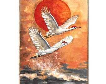 May include: Watercolor painting of two cranes in flight against a vibrant orange sunset and a large red sun. The birds have white and gray feathers with red markings. The artwork is framed in a wooden frame.