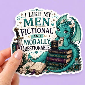 Puede incluir: Una pegatina con un dragón turquesa sentado sobre libros. El texto dice: «ME GUSTAN MIS HOMBRES DE FICCIÓN Y MORALMENTE CUESTIONABLES». Los libros tienen títulos como «Enemies to Lovers» y «Slow Burn».