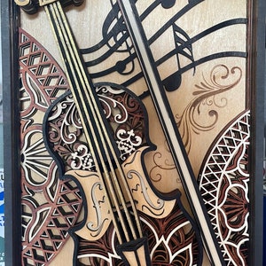 Puede incluir: Una pieza de arte de pared de madera con un violín tallado en capas, intrincadamente, con notas musicales y un diseño decorativo. El violín está hecho de diferentes tonos de madera, incluyendo marrón, rojo y dorado.