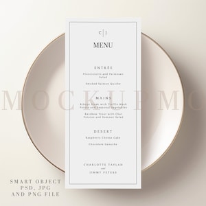 May include: A minimalist menu card with a white background, featuring a simple black border and elegant typography. The menu includes Entrée, Mains, and Dessert options, with the names of the dishes listed below each category. The card is placed on a white plate with a gold rim.