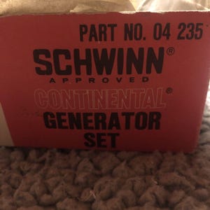 Puede incluir: Una caja roja con el texto "PART NO. 04 235" y "SCHWINN® APPROVED CONTINENTAL® GENERATOR SET" en letras negras.