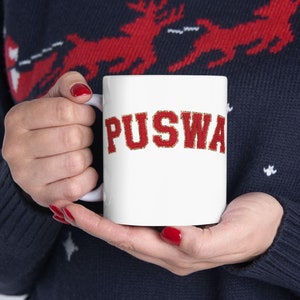 May include: White ceramic mug with a red and gold glitter design that says "PUSWA" on the front.