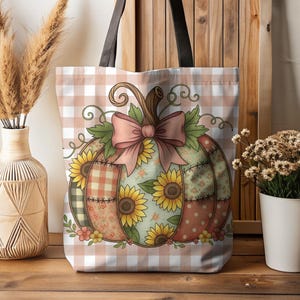 Könnte beinhalten: Eine Tragetasche mit einem Kürbisdesign. Der Kürbis ist mit Sonnenblumen, einer rosa Schleife und Patchwork-Mustern verziert. Die Tasche hat schwarze Griffe und einen pfirsichfarbenen und weißen Karohintergrund.