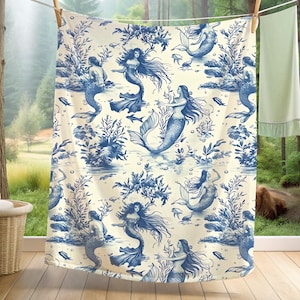 May include: A white fabric shower curtain with a blue and white pattern of mermaids and seashells. The pattern is reminiscent of a toile design.