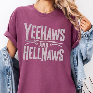 May include: A maroon t-shirt with the text "Yeehaws and Hellnaws" printed in white.