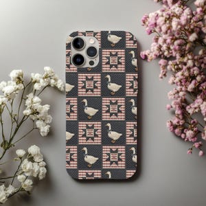 May include: A phone case with a patchwork design. The case features white geese wearing blue ribbons, set against a dark background with red and white star and stripe patterns. The case has a camera cutout.