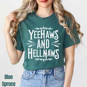 May include: Blue spruce t-shirt with the text "Yeehaws and Hellnaws" in white. The shirt has a crew neck and short sleeves. The text is in a decorative font with arrows and flourishes.