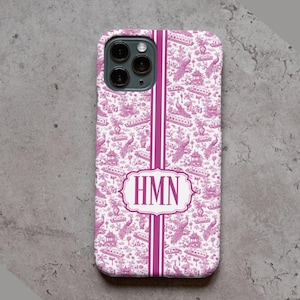May include: A smartphone case featuring a magenta and white toile pattern with illustrations of pagodas and peacocks. A vertical magenta stripe runs down the centre, interrupted by a white rectangular frame containing the monogram letters HMN.