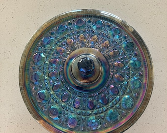 May include: A round iridescent blue glass cake plate with a raised center and a decorative pattern of circles and diamonds.