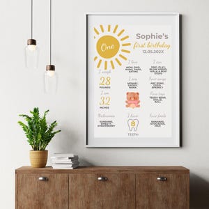 May include: A yellow and white printable first birthday chart for a baby girl named Sophie. The chart includes details about her age, weight, height, favorite foods, songs, and toys. It also includes a picture of a teddy bear and a tooth.