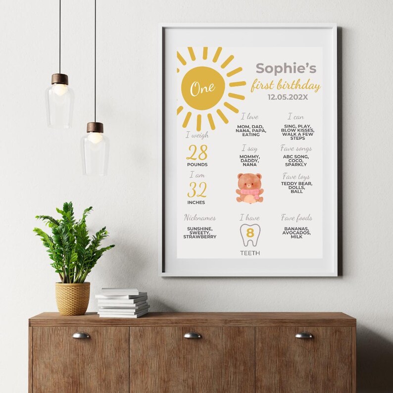 May include: A yellow and white printable first birthday chart for a baby girl named Sophie. The chart includes details about her age, weight, height, favorite foods, songs, and toys. It also includes a picture of a teddy bear and a tooth.