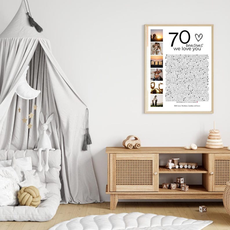 Pode incluir: Uma impress&atilde;o emoldurada com o texto "70 raz&otilde;es pelas quais te amamos" e v&aacute;rias fotos pequenas. A impress&atilde;o &eacute; exibida em um arm&aacute;rio de madeira clara em uma sala com uma cama com dossel cinza e brinquedos decorativos.