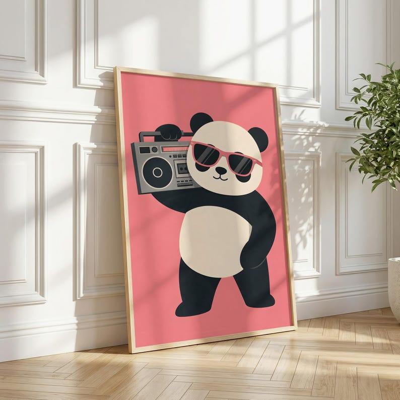 May include: A framed wall art print featuring a cartoon panda with black and white fur, wearing pink sunglasses, and holding a grey boombox on its shoulder. The background of the illustration is a solid, vibrant pink color, presented in a light wood frame.