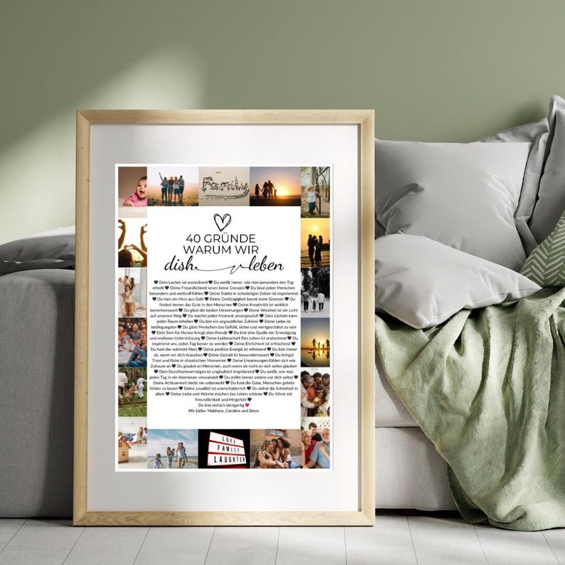 May include: A framed print with a light wood frame. The print features a collage of family photos and text in German that reads "40 Gr&uuml;nde warum wir dish leben." The print is displayed on a bed with pillows and a green blanket.