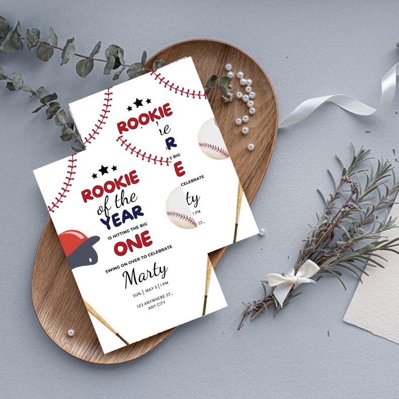 May include: Baseball-themed birthday party invitation with red, white, and blue colors. The invitation says "Rookie of the Year is hitting the big one" and includes a baseball, bat, and a baseball cap. The invitation is for Marty's birthday party on Sunday, May 5th at 1 PM.
