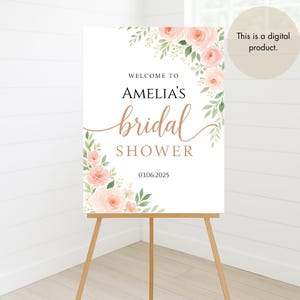Op de afbeelding: Een afdrukbaar bruidsdouchebord met een bloemenontwerp in roze en groene tinten. Het bord staat er: "Welkom bij Amelia's bruidsdouche 03.06.2025".