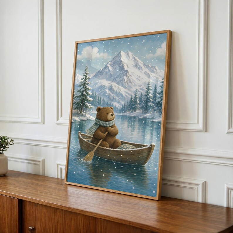 May include: A framed wall art print depicting a brown bear wearing a blue and white plaid scarf, sitting in a wooden rowboat on a calm lake. The background features snow-covered mountains and evergreen trees under a light snowfall.