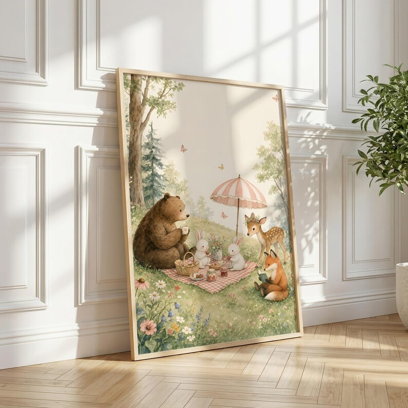 May include: A framed wall art print featuring a watercolor illustration of a brown bear, two white rabbits, a fawn, and a fox having a picnic on a grassy meadow. The scene includes a pink and white striped umbrella, wildflowers, and butterflies.