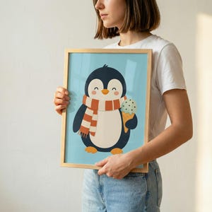 May include: A framed wall art print featuring a cartoon penguin with a black and white body, wearing an orange and white striped scarf, and holding a light green ice cream cone with chocolate chips against a solid light blue background.