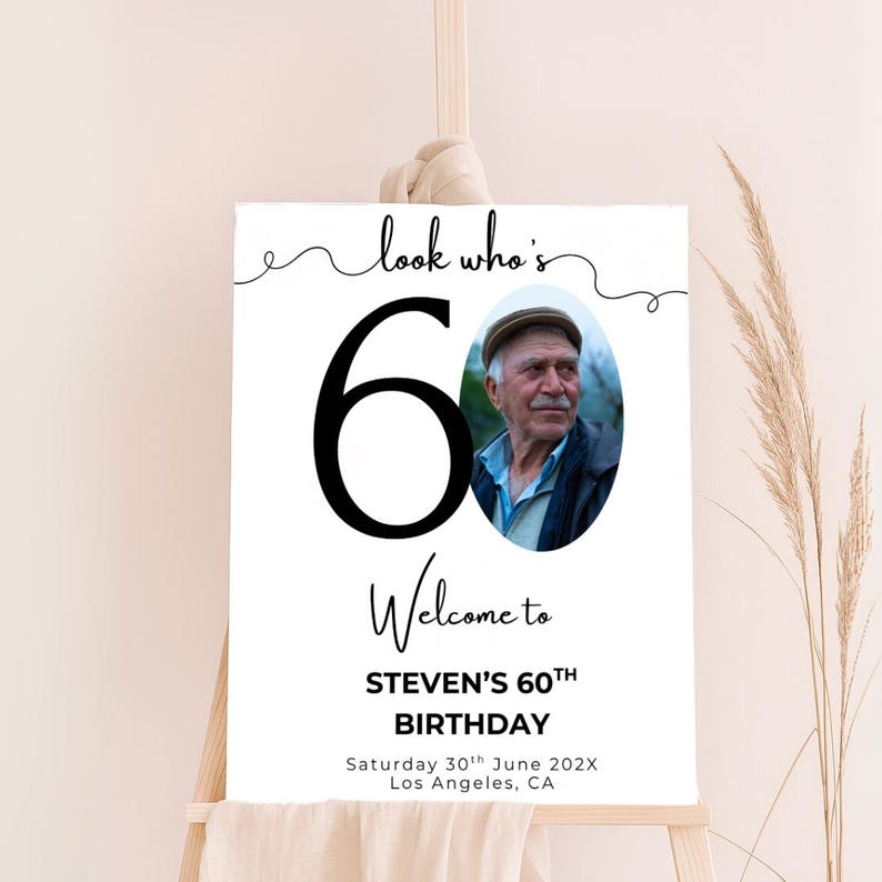 May include: A white welcome sign with a black number 60 and the text "look who's 60". A photo of a man is in the background. The text "Welcome to STEVEN'S 60TH BIRTHDAY" is below the number. The date and location are listed below the birthday text.