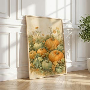 May include: A rectangular framed wall art print featuring a watercolor illustration of several pumpkins in shades of orange and muted green, surrounded by autumn foliage, vines, and small yellow flowers against a soft, light-toned background.