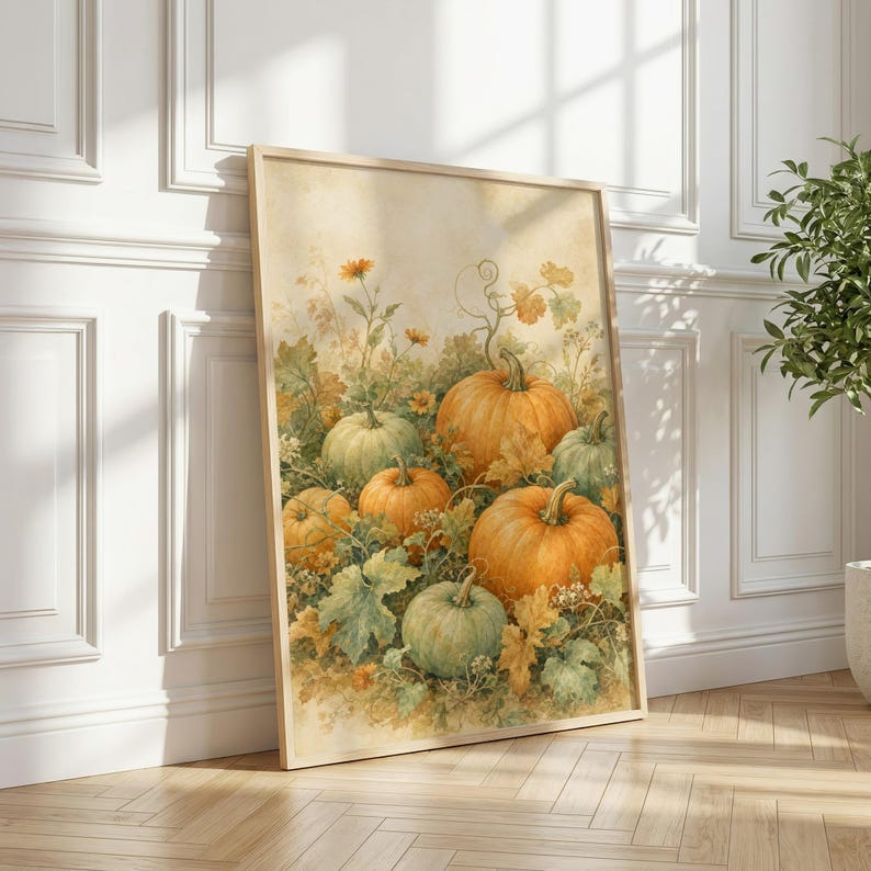 May include: A rectangular framed wall art print featuring a watercolor illustration of several pumpkins in shades of orange and muted green, surrounded by autumn foliage, vines, and small yellow flowers against a soft, light-toned background.