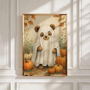 May include: A framed wall art print featuring a brown bear wearing a white ghost costume made from a sheet. The bear is surrounded by several orange pumpkins and autumn leaves on the ground, set against a light, neutral-toned background.