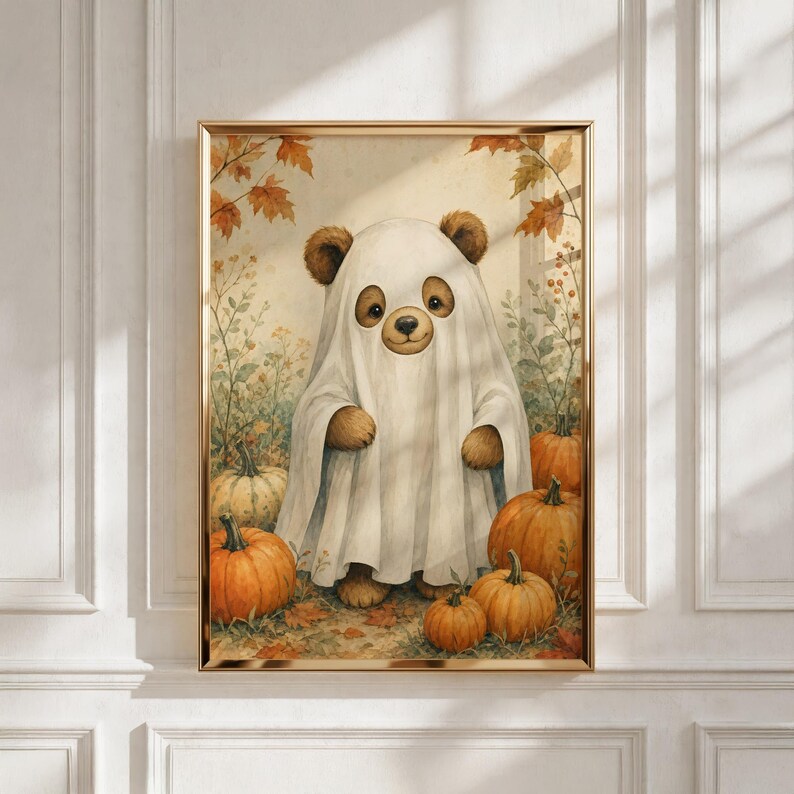 May include: A framed wall art print featuring a brown bear wearing a white ghost costume made from a sheet. The bear is surrounded by several orange pumpkins and autumn leaves on the ground, set against a light, neutral-toned background.