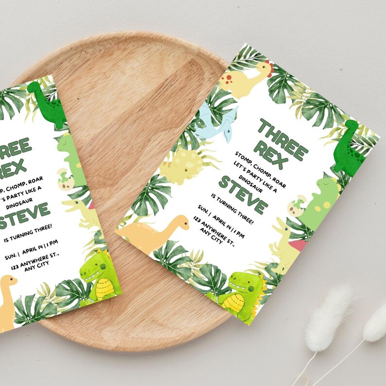 May include: Two green and white dinosaur-themed birthday party invitations featuring green, yellow, and blue dinosaurs. The invitations read "Three Rex Steve is turning three!" and include the date, time, and address of the party.