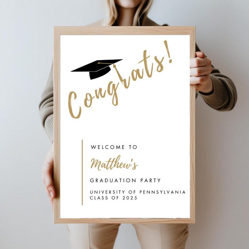 K&ouml;nnte beinhalten: Ein wei&szlig;es Schild f&uuml;r eine Graduierungsparty mit goldener Schrift, auf dem "Herzlichen Gl&uuml;ckwunsch!" und eine schwarze Graduation Cap steht. Das Schild sagt auch "Willkommen zur Graduierungsparty von Matthew, University of Pennsylvania, Klasse von 2025."