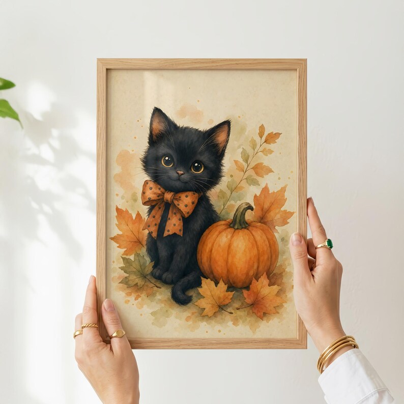 May include: A framed watercolor print featuring a fluffy black kitten with large golden eyes wearing an orange polka-dot bow tie, sitting next to a round orange pumpkin surrounded by scattered autumn leaves in shades of yellow and brown.