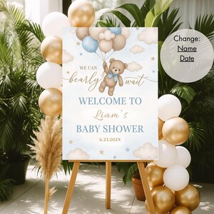 May include: A blue and white baby shower welcome sign with a teddy bear holding balloons. The sign says "We can bearly wait" and "Welcome to Liam's Baby Shower".