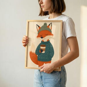 May include: A framed art print featuring a cartoon fox with orange fur, wearing a dark green knit beanie and a matching sweater, holding a brown coffee cup. The fox has closed eyes and a gentle smile, set against a light cream-colored background.