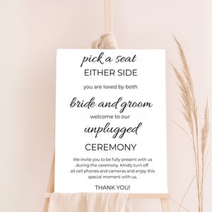 May include: White sign with black text that reads "pick a seat either side you are loved by both bride and groom welcome to our unplugged ceremony we invite you to be fully present with us during the ceremony. Kindly turn off all cell phones and cameras and enjoy this special moment with us. thank you!"