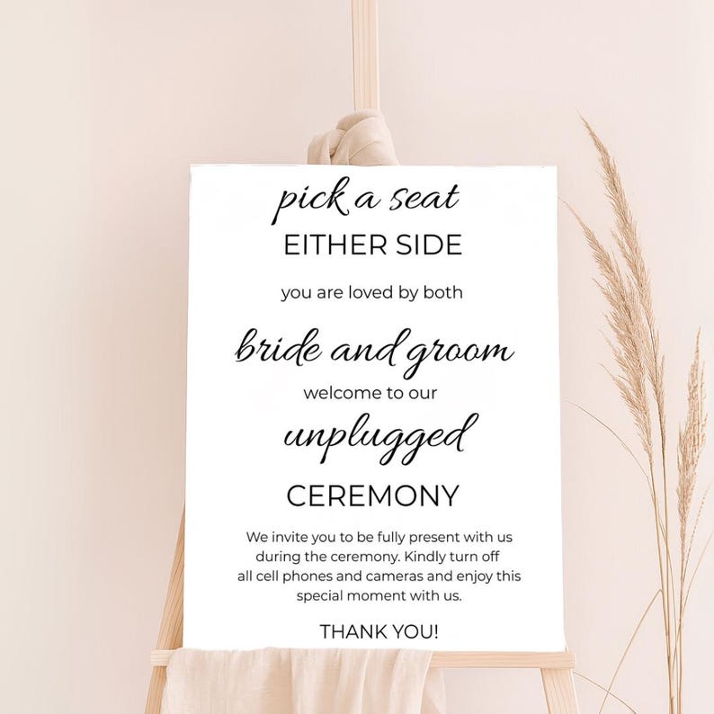May include: White sign with black text that reads "pick a seat either side you are loved by both bride and groom welcome to our unplugged ceremony we invite you to be fully present with us during the ceremony. Kindly turn off all cell phones and cameras and enjoy this special moment with us. thank you!"