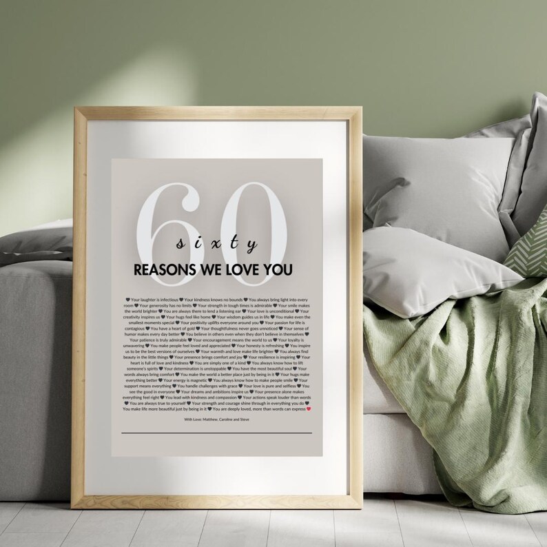 May include: A framed print with a beige background and white text. The print features the number 60 with the word "sixty" below it. The text "Reasons We Love You" is below the number. The print is surrounded by a wooden frame.